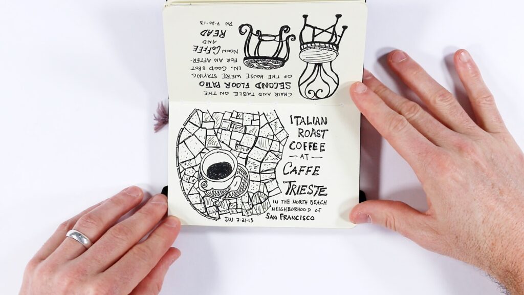 Two hands hold open a small sketchbook. The top page (upside down) shows the chair and table sketch from the previous spread. The bottom page features a richly detailed circular mosaic-style drawing of a coffee cup, with hand-lettered text reading "Italian Roast Coffee at Caffe Trieste in the North Beach neighborhood of San Francisco," dated DN 7-21-13."